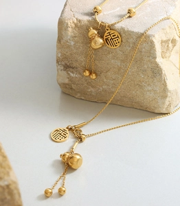 Macro detail of golden gourd and Fu character pendant on a stainless steel necklace