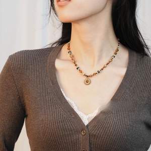 Gros plan du collier de perles bohème avec pendentif soleil doré et œil de chat