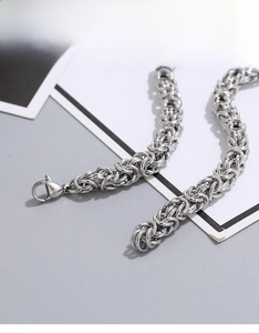 Detail of a thick silver metal lobster clasp and durable byzantine chain for men