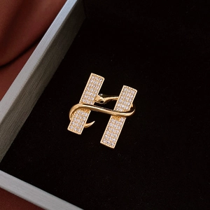 Détail macro de la broche en H avec placage d'or et zircons blancs sertis pavé