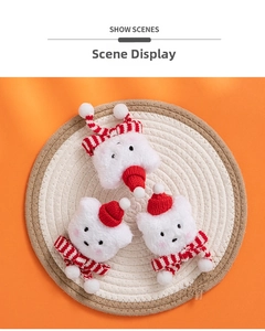 Three plush white Christmas cat charms with red hats and scarves on a woven mat