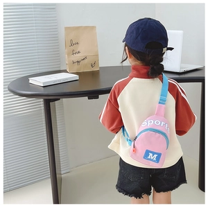 Sac bandoulière rose enfant en nylon avec sangle bleue porté par un mannequin enfant