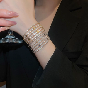 Detail of layered gold and silver rhinestone bracelets with metallic disc charms