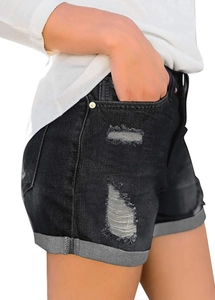 Detail of black distressed denim shorts featuring ripped textures and folded hems for women