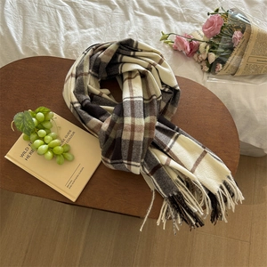 Classic earth-tone plaid scarf with tassels on a wooden tray for cozy winter styling