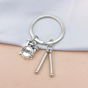 Detailed close-up of a silver music-themed keychain featuring a drum set and drumsticks