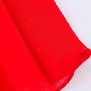 Vue détaillée du tissu en mousseline rouge montrant l'ourlet roulé et la texture fine