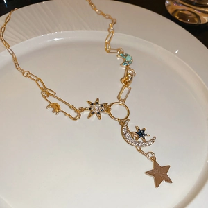 Détail du collier étoile et lune dorées avec strass bleus et fermoir en épingle à nourrice