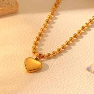 Macro shot of gold stainless steel heart pendant necklace on a natural textured surface