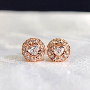 Close-up of heart-shaped zircon earrings with rose gold plating and halo setting