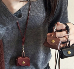 Miniature leather pouch necklaces in burgundy, brown and black on a grey sweater