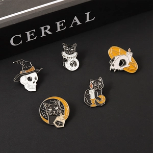 Detailed close-up of gothic cat and skull enamel pins in black and gold finish