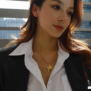 Close-up of golden star pendant with bead chain on a professional suit outfit