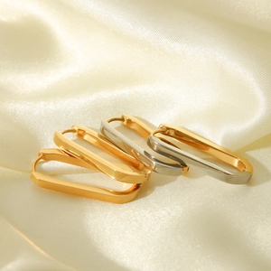 Close-up of rectangle gold and silver stainless steel earrings on silk background