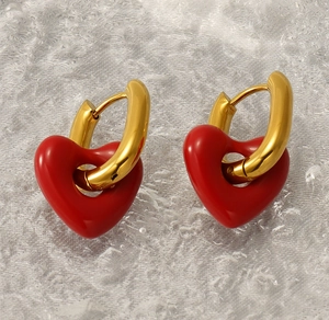 Close-up of vintage U-shaped gold hoop earrings with polished red enamel heart pendants