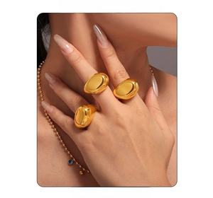Close-up of model wearing chunky irregular gold rings with matching beaded necklace