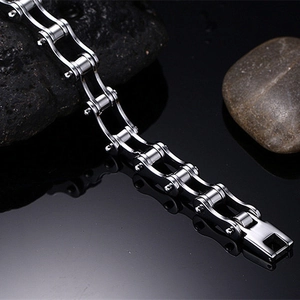Close-up of silver stainless steel bicycle chain bracelet on reflective dark stone surface