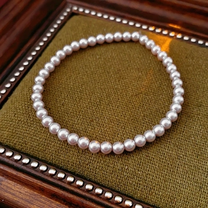 Detail of rose-colored pearl bracelet displayed on elegant vintage green fabric