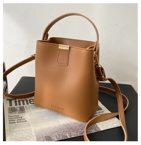 Detail der karamellfarbenen Beuteltasche mit Goldverschluss und Fashion-Prägung auf Schwarz