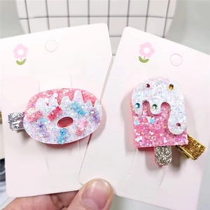 Detail of glitter pink donut and popsicle hair clips with colorful gemstone accents