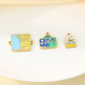 Detail of beach-themed enamel pendants with palm tree and sunset on a ceramic plate