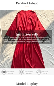Detail of red satin robe featuring black lace cuffs and a silk-like glossy texture