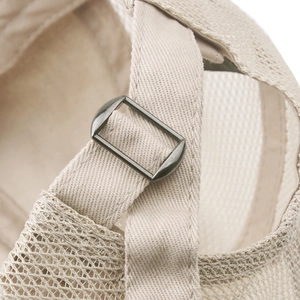 Detailed macro view of the adjustable metal buckle and breathable mesh on the beige beret