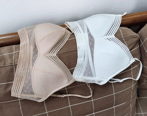 Flat lay detail of mesh polka dot bras in nude and white with adjustable straps