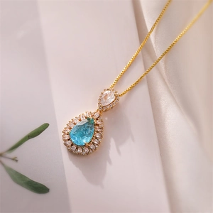 Detailed shot of double layer gold necklace with blue teardrop stone and pavé diamonds
