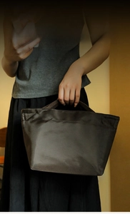 Dettaglio della borsa pranzo in nylon antracite con manico intrecciato e logo del marchio