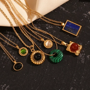 Detailed close-up of multiple 18K gold plated necklaces with natural gemstones on silk fabric