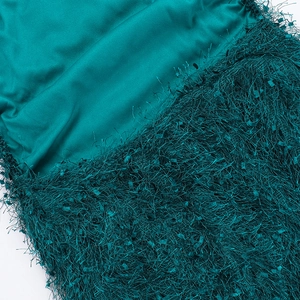 Detail shot of emerald green satin fabric and high-density long fringe on the dress