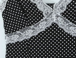 Detailed close-up of white lace trim on black polka dot dress with invisible zipper