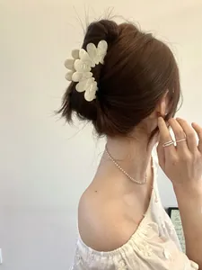 Close-up of elegant cream-colored acetate flower hair claw with marble texture on model