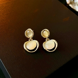 Detailed view of golden double circle earrings with cat-eye opal on a wooden background