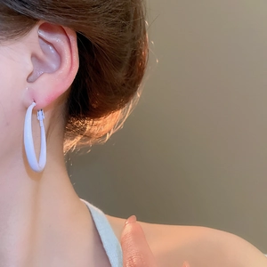Close-up of minimalist white circular hoop earrings worn by a model for a stylish look