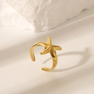 Detailaufnahme des goldenen Seestern-Rings auf weißem strukturiertem Stein-Hintergrund