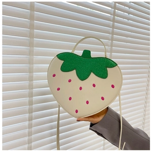 Detail of strawberry shaped crossbody bag with glitter green leaves and pink dots