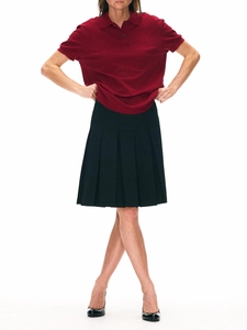 Academic style outfit with dark red polo shirt and black pleated midi skirt on model
