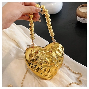 Dettaglio borsa da sera a forma di cuore in metallo dorato con superficie testurizzata