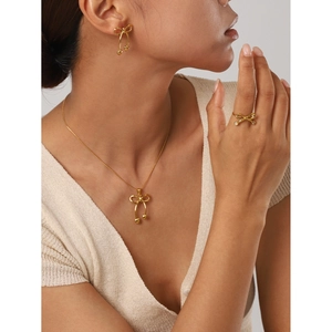 Golden bow-shaped necklace, earrings and ring jewelry set on model with a glossy finish