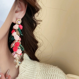 Détail de boucles d'oreilles pendantes à fleurs rouges et cristaux sur un modèle