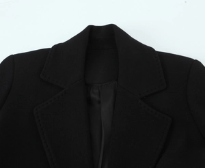 Detailed close-up of a notched lapel on a black wool blend blazer with refined stitching