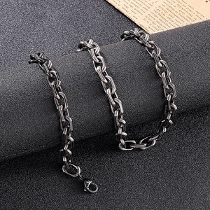 Close-up of industrial silver-toned chunky chain link necklace on a textured black surface