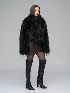 Full-body shot of long black faux fur coat styled with brown leather skirt and boots