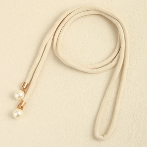 Close-up of beige velvet waist rope with golden metal caps and elegant imitation pearls