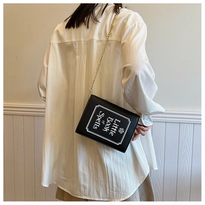 Gothic book-shaped crossbody bag with Little Book of Spells print and gold chain strap