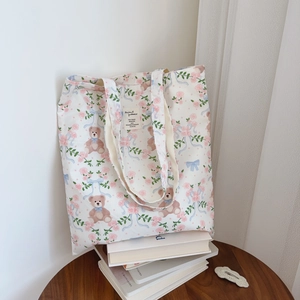 Sac fourre-tout en coton avec fleurs roses, ours et nœuds bleus sur un bureau