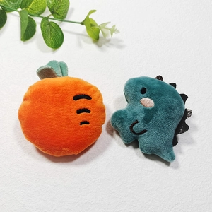 Close-up of plush carrot and green dinosaur toys on a white textured background