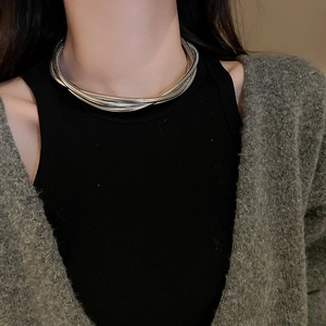 Close-up of layered silver snake chain necklace worn on neck with metallic shine